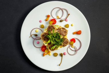 Beyaz tabakta etli ve malzemeli salata.