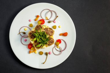 Beyaz tabakta etli ve malzemeli salata.