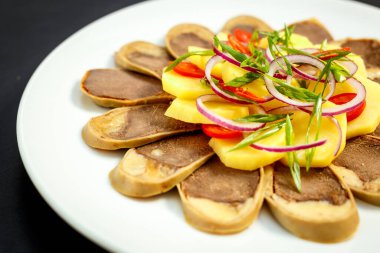 Kazak mutfağı, haşlanmış patates, soğan ve otlu et, beyaz tabakta.