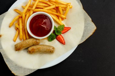 Kızarmış patates ve soslu tavuk sosisi.