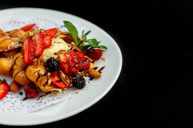 Waffle, böğürtlenli, fındıklı ve taze meyveli bir İtalyan dondurması topu.