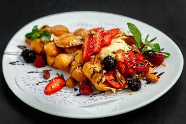 Waffle, böğürtlenli, fındıklı ve taze meyveli bir İtalyan dondurması topu.