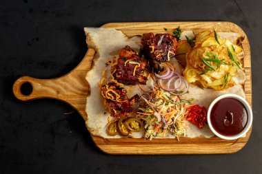 Tahtaya konmuş ev yapımı patates, salata ve sos ile iştah açıcı pirzola.