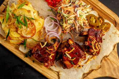 Tahtaya konmuş ev yapımı patates, salata ve sos ile iştah açıcı pirzola.