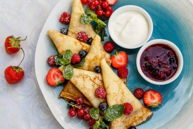 Taze böğürtlenli krep, reçel ve sos süslemeli masaya.