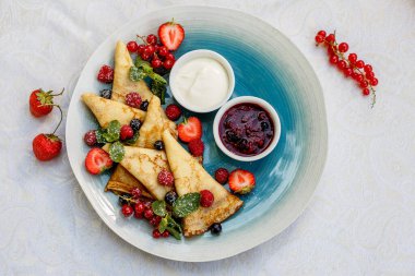 Taze böğürtlenli krep, reçel ve sos süslemeli masaya.