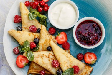 Taze böğürtlenli krep, reçel ve sos süslemeli masaya.