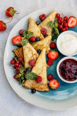 Taze böğürtlenli krep, reçel ve sos süslemeli masaya.