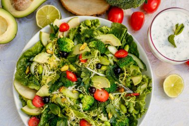 Detoks, brokoli ve avokado ile sağlıklı sebze salatası, süslü bir masada sağlıklı yiyecekler.