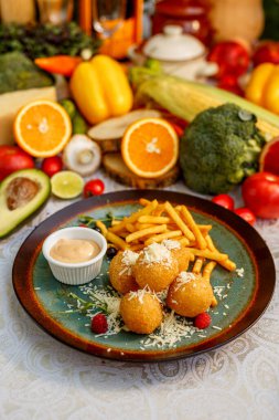 Yumuşak eritilmiş peynirli çıtır patates topları ve dekore edilmiş masada patates kızartması.