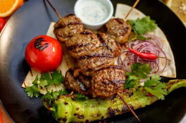 Süslü bir masada pide ekmekli kebap ve ızgara sebze.