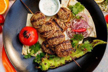 Süslü bir masada pide ekmekli kebap ve ızgara sebze.