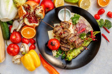 Süslü bir masada pide ekmekli kebap ve ızgara sebze.