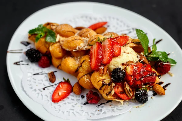 Waffle, böğürtlenli, fındıklı ve taze meyveli bir İtalyan dondurması topu.