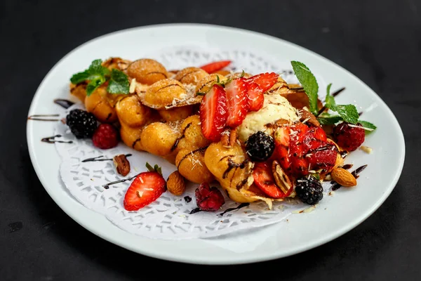 Waffle, böğürtlenli, fındıklı ve taze meyveli bir İtalyan dondurması topu.