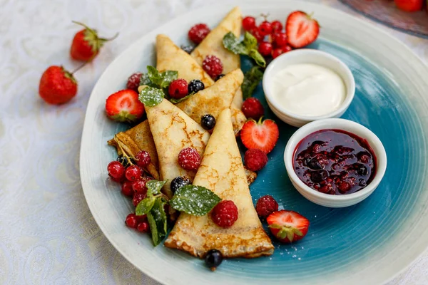 Taze böğürtlenli krep, reçel ve sos süslemeli masaya.