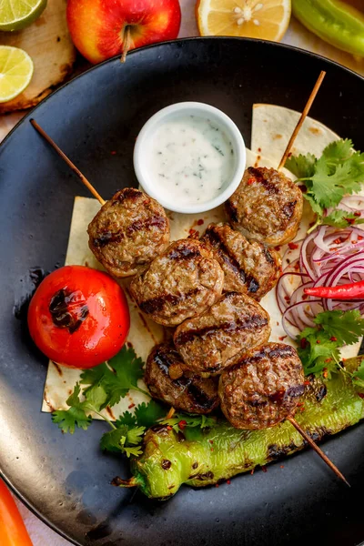 Süslü bir masada pide ekmekli kebap ve ızgara sebze.