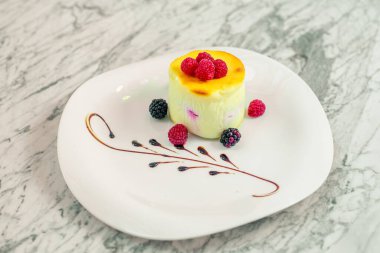 Beyaz tabakta böğürtlenli peynirli kek.