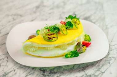 Beyaz tabakta peynirli ve sebzeli omlet