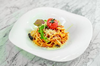 Beyaz tabakta peynirli ve sebzeli İtalyan makarnası.