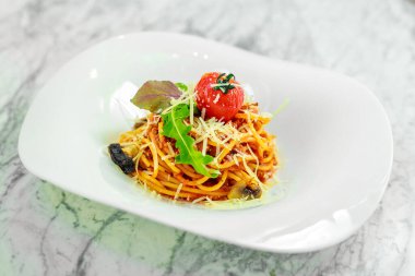 Beyaz tabakta peynirli ve sebzeli İtalyan makarnası.