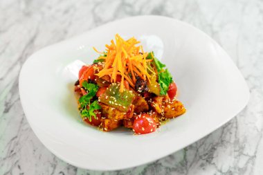 Kızarmış tofu, susam tohumları ve sebzeler beyaz tabakta.