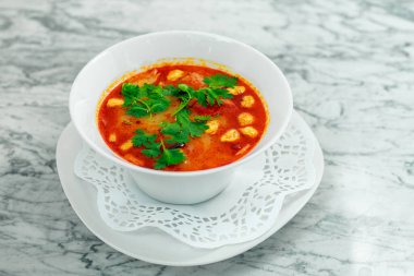 Tavuklu çorba, mantarlar ve beyaz tabakta bitkiler, güzel bir servis.