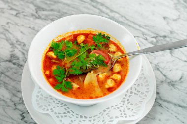 Tavuklu çorba, mantarlar ve beyaz tabakta bitkiler, güzel bir servis.