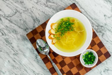 Tavuklu çorba, mantarlar ve beyaz tabakta bitkiler, güzel bir servis.