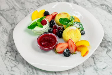 Beyaz tabakta meyve ve reçelli süzme peynir krepleri.