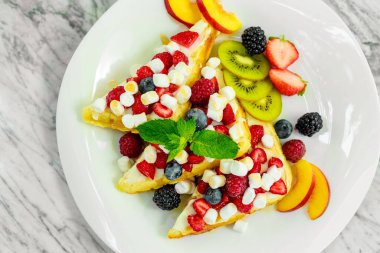 Beyaz tabakta fındıklı, çikolatalı ve meyveli Belçika waffleları.