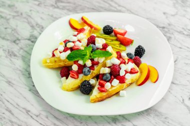 Beyaz tabakta fındıklı, çikolatalı ve meyveli Belçika waffleları.