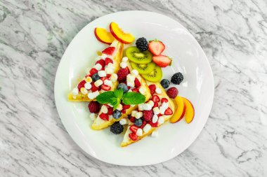 Beyaz tabakta fındıklı, çikolatalı ve meyveli Belçika waffleları.