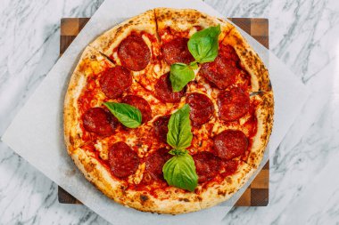 İtalyan pizzası, mozzarella peyniri ve fesleğen ile mermer bir masada.