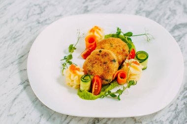 Havyarlı balık köftesi ve mermer bir masada sebze.