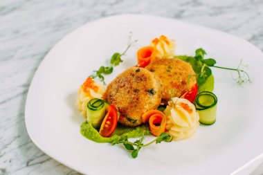 Havyarlı balık köftesi ve mermer bir masada sebze.