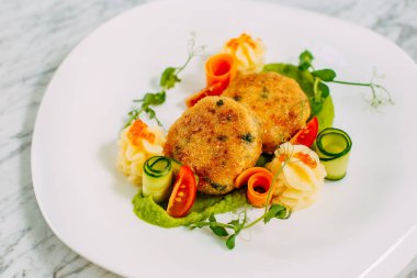 Havyarlı balık köftesi ve mermer bir masada sebze.