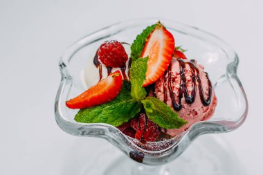 Beyaz arka planda meyveli ve şuruplu üç top dondurma.