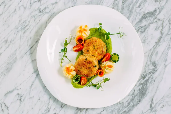 fish cakes with caviar and vegetables on a marble table