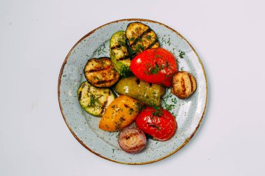 Beyaz arka planda ızgara sebze, domates, patlıcan ve biber tabağı.