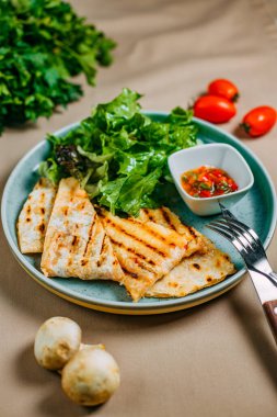 Soslu quesadilla ve süslü bir masada sebzeli marul.