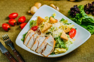 Süslü bir masada tavuk ve sebzeli Sezar salatası.