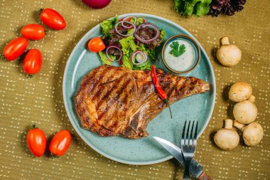 Sebzeli biftek ve soslu bir tabak, süslü bir masada.