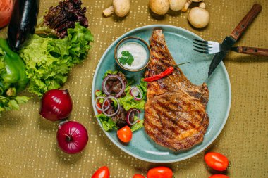 Sebzeli biftek ve soslu bir tabak, süslü bir masada.