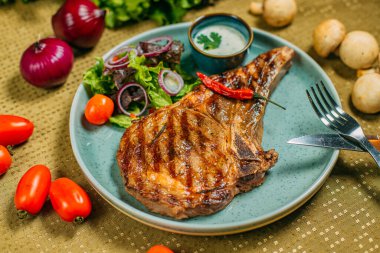 Sebzeli biftek ve soslu bir tabak, süslü bir masada.