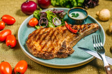 Sebzeli biftek ve soslu bir tabak, süslü bir masada.