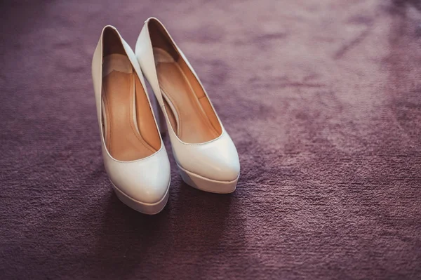 Brud bröllop skor med höga klackar och lysande silverörhängen på fårakläder — Stockfoto