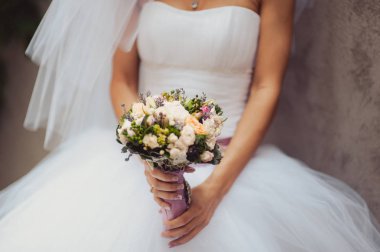 Gelin düğün töreninde büyük bir buket tutuyor.