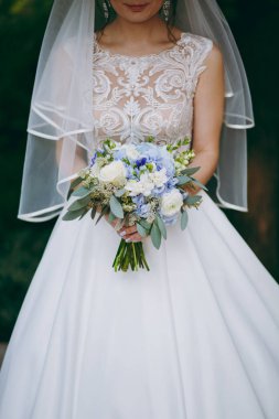 Gelin düğün töreninde büyük bir buket tutuyor.