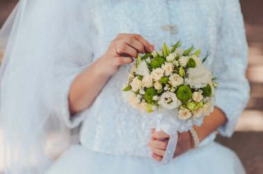 Gelin düğün töreninde büyük bir buket tutuyor.